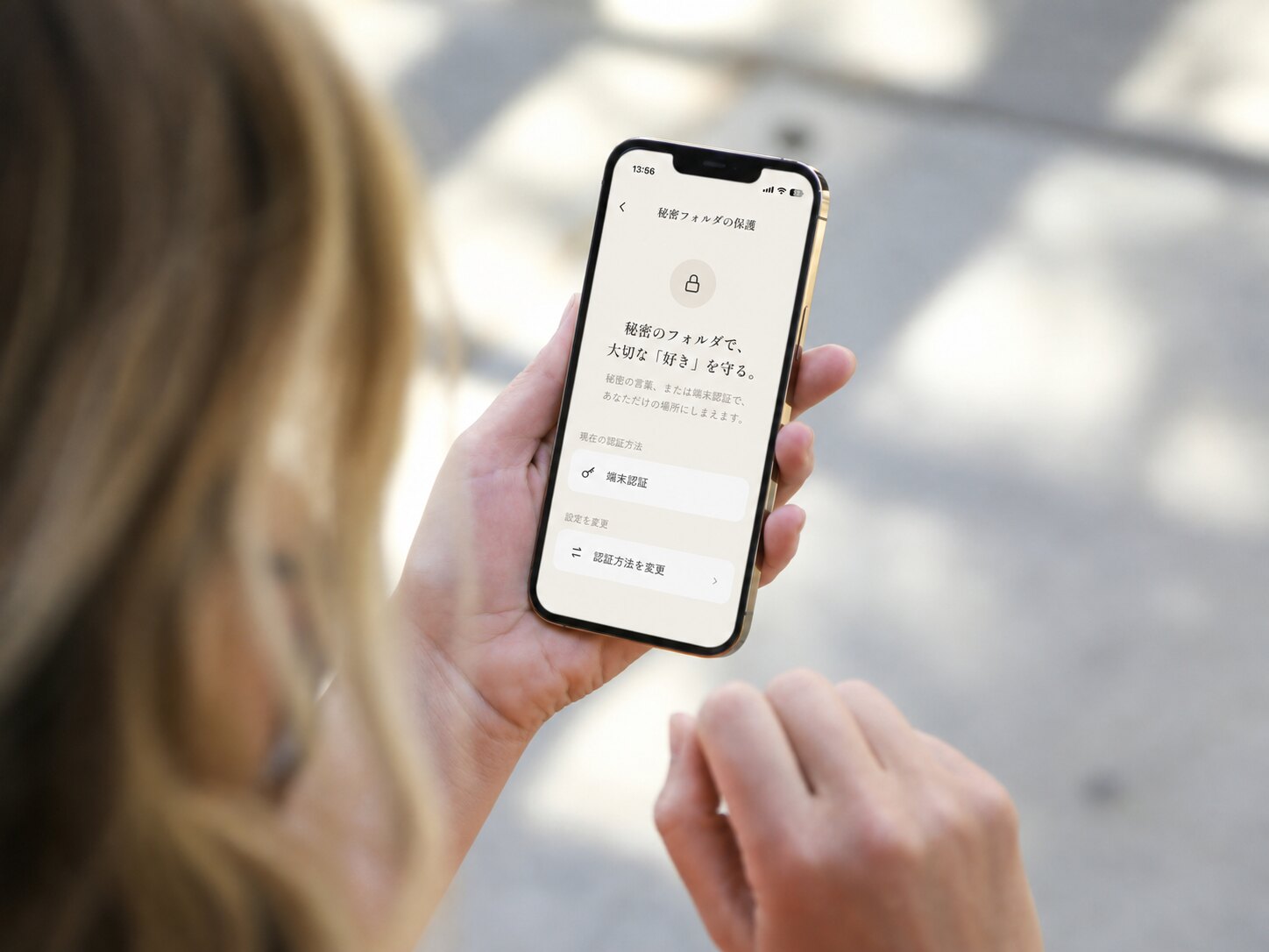 好日の「秘密フォルダの保護」画面を開いたiPhoneを、手に持って見ている様子